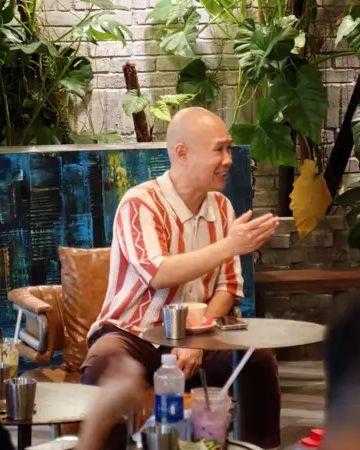 Anh Võ Hoài Nam ngồi ở bàn cà phê, cười và trao đổi với những người ngồi quanh.